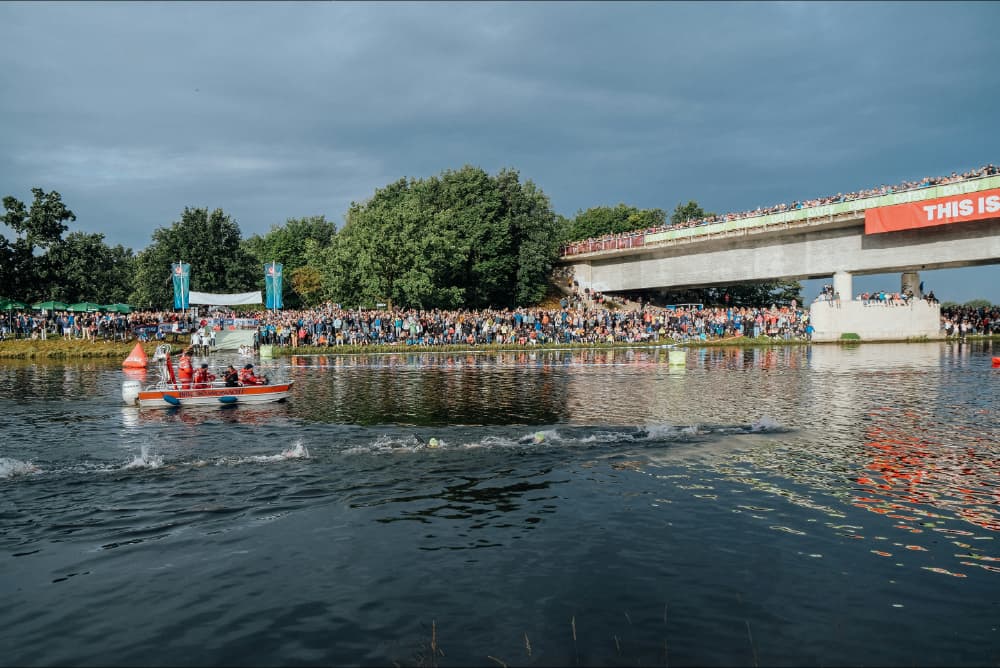 Swimmers racing the canal swim at Challenge Roth, crowds lining the bank